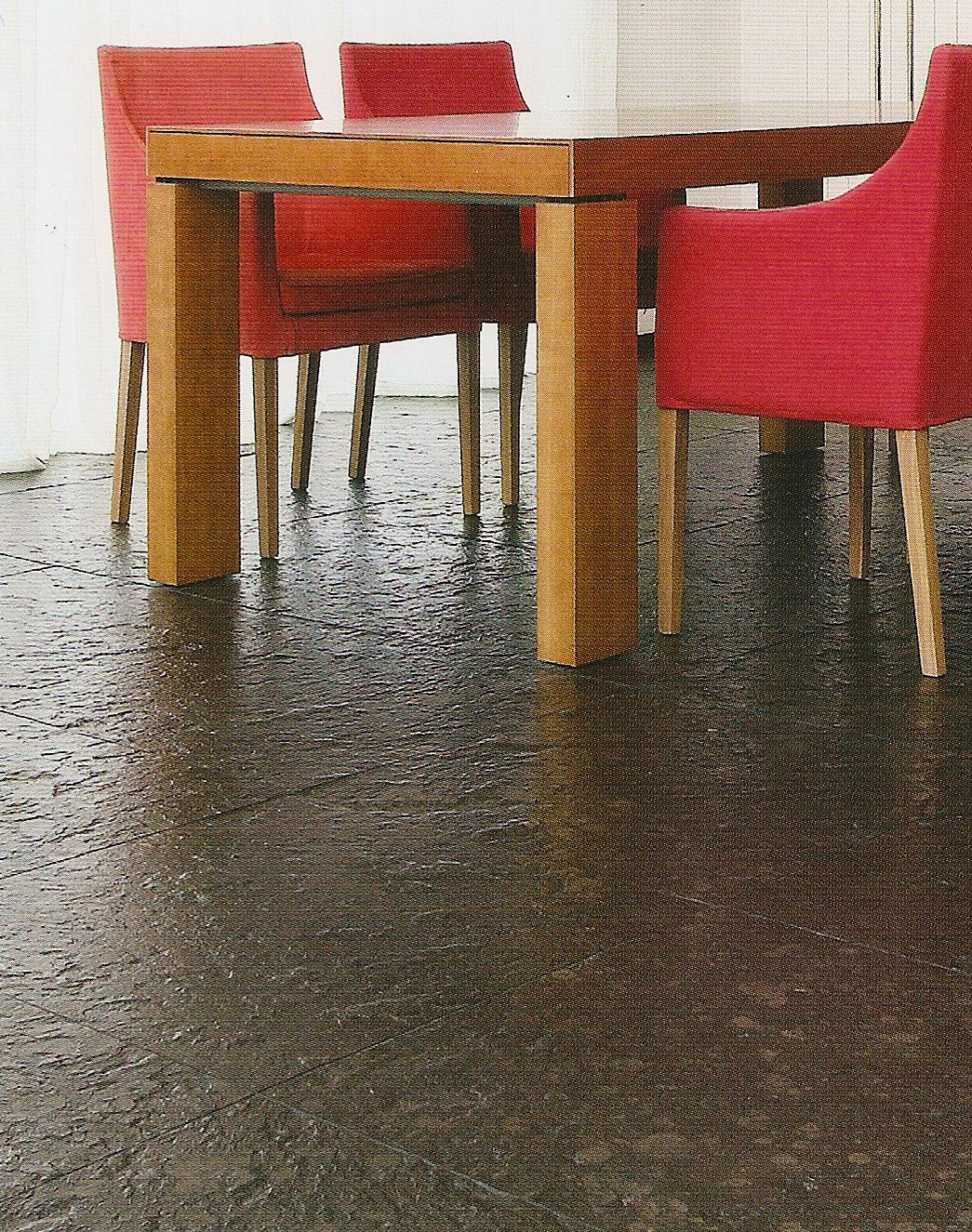 Holztisch mit roten Stühlen auf Schieferfliesen